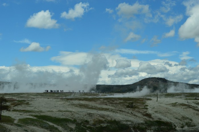 Tiny people in the steam from a geyser basin